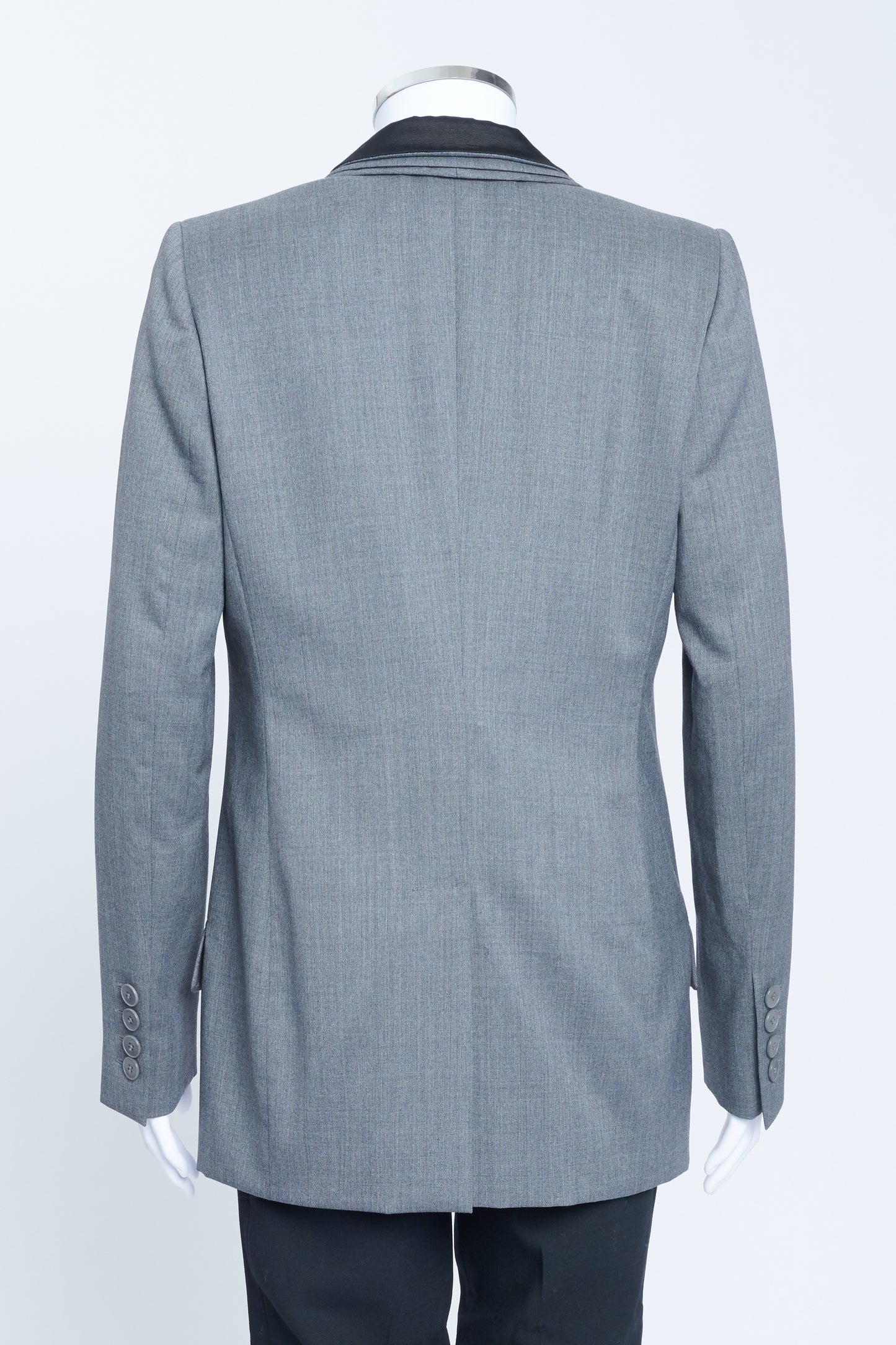 Grey wool tuxedo style jacket with triple elongated lapel, grosgrain detail and hook and eye fastening.